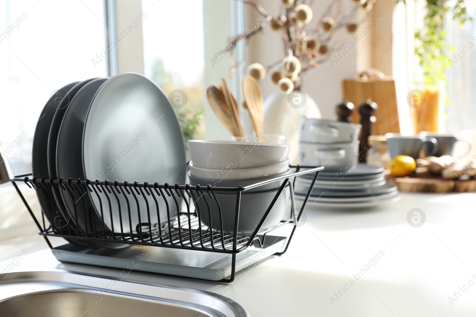 Photo of Clean dishware on white table in modern kitchen