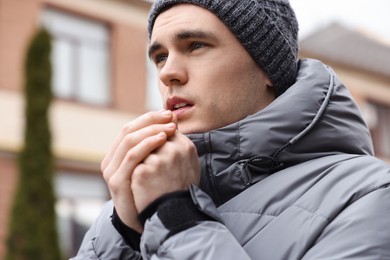 Photo of Sick young man coughing on city street. Cold symptoms