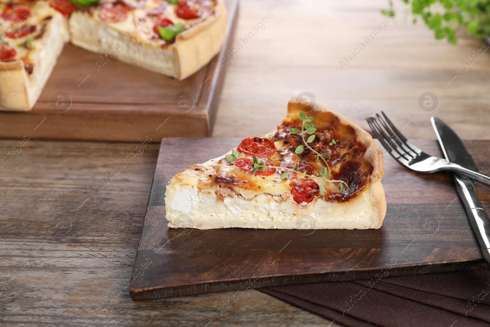 Photo of Piece of delicious homemade quiche with prosciutto, tomatoes and microgreens served on wooden table