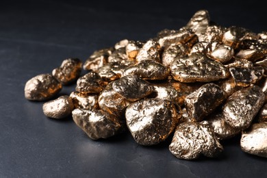 Pile of gold nuggets on black table, closeup