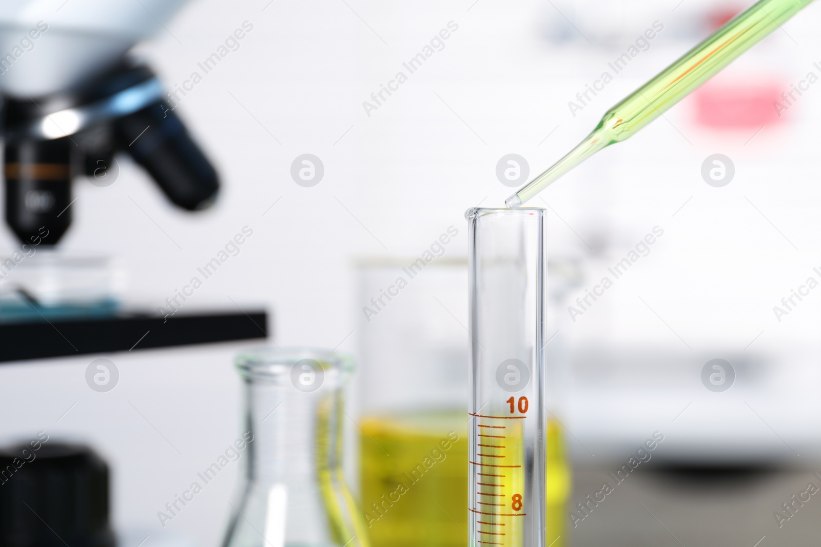 Photo of Laboratory analysis. Dripping liquid into test tube on table, closeup