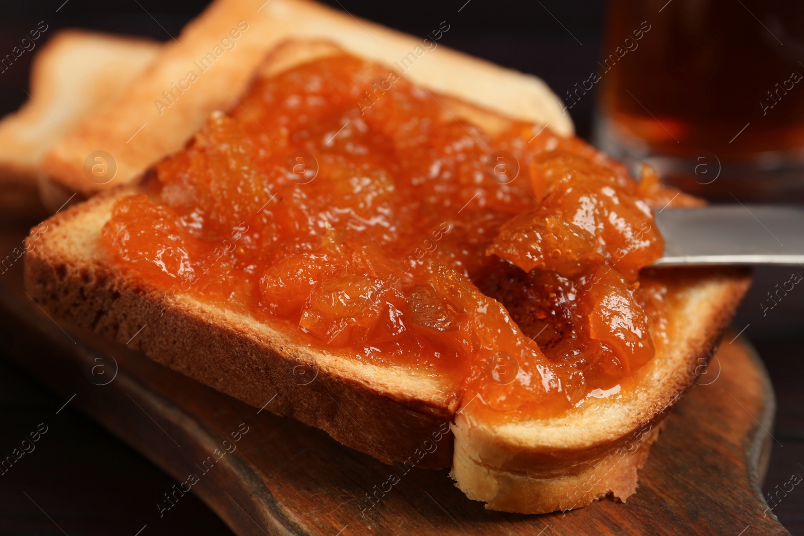 Photo of Delicious toast with jam on wooden board, closeup