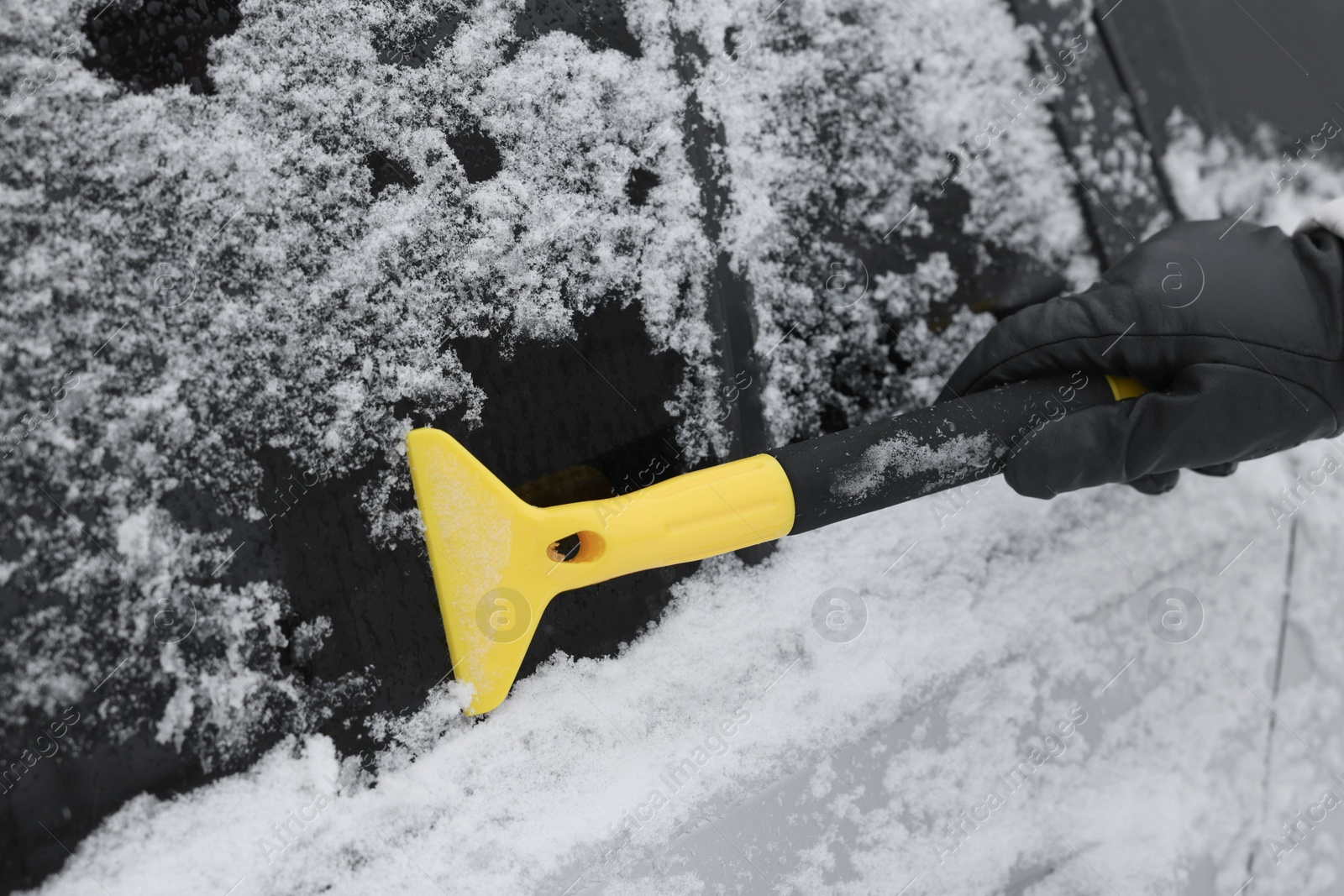 Photo of Man cleaning snow from car outdoors, closeup