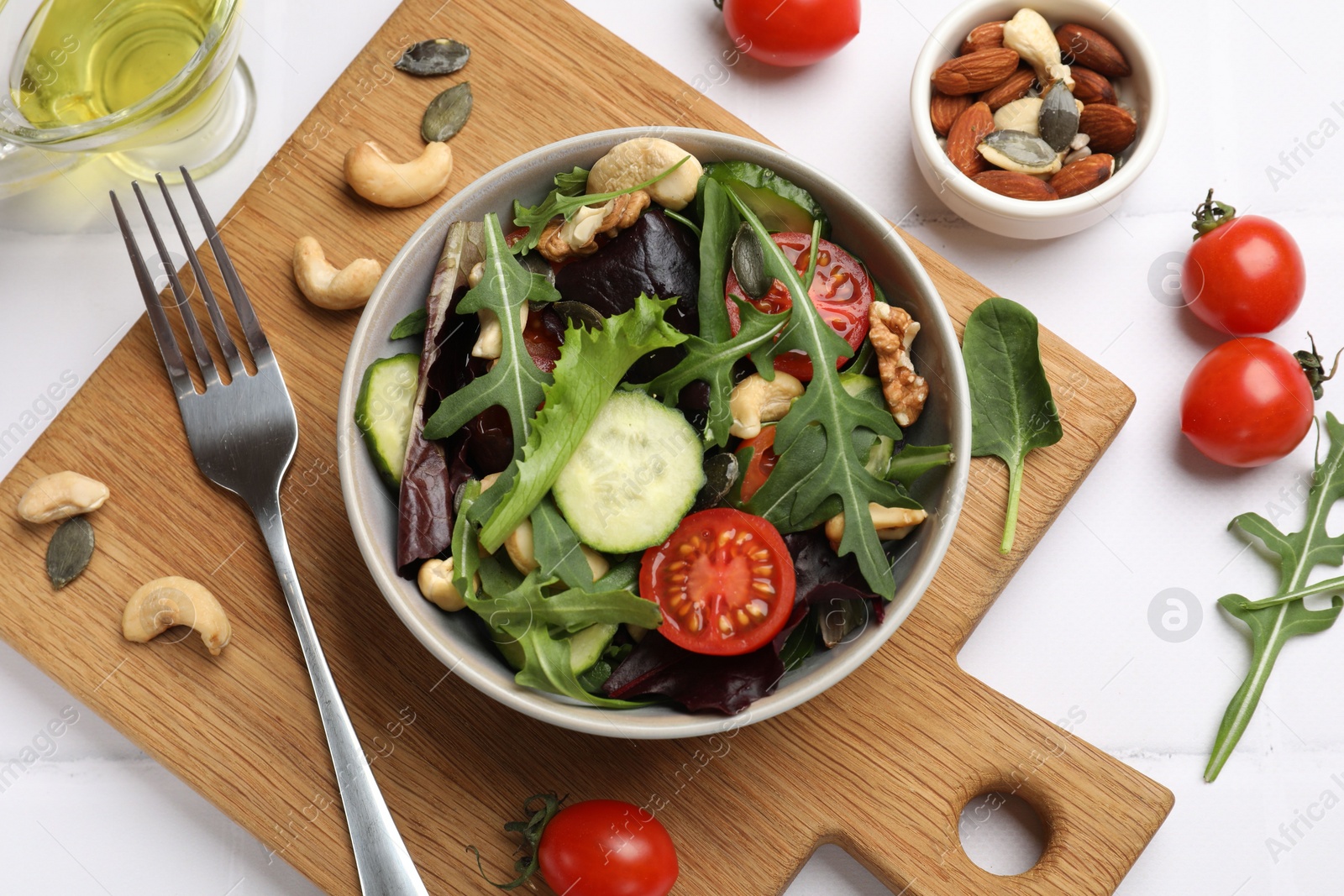 Photo of Tasty fresh vegetarian salad and ingredients on white tiled table, flat lay