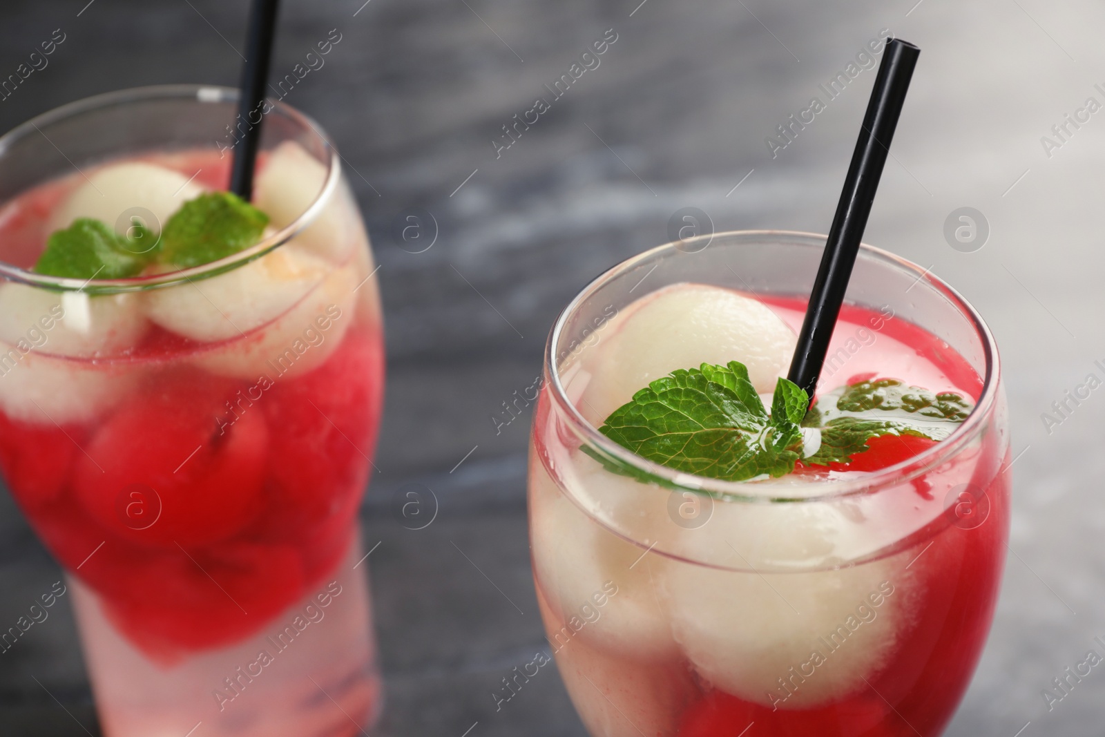 Photo of Glasses with tasty melon and watermelon ball drinks on dark table