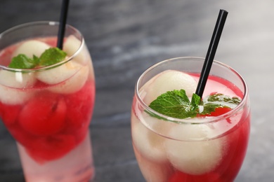 Photo of Glasses with tasty melon and watermelon ball drinks on dark table