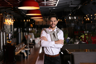 Photo of Young business owner standing near counter in his cafe