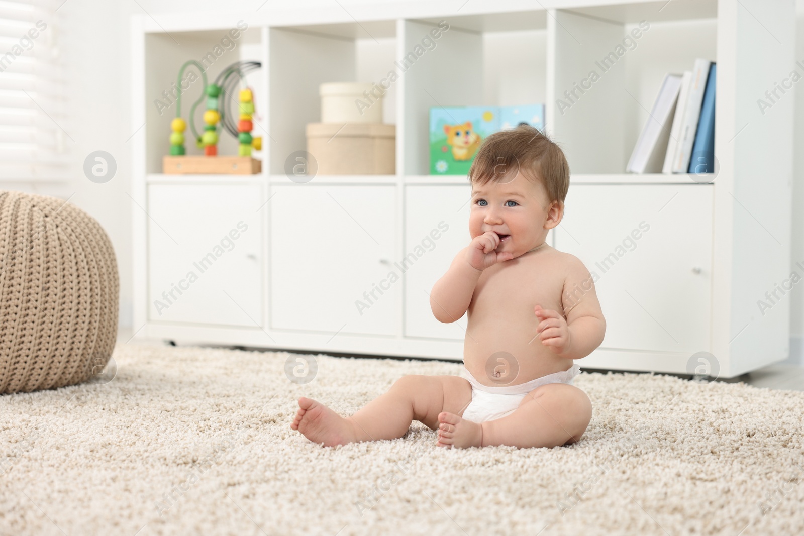 Photo of Cute baby boy sitting on carpet at home