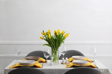 Beautiful Easter table setting with yellow tulips indoors