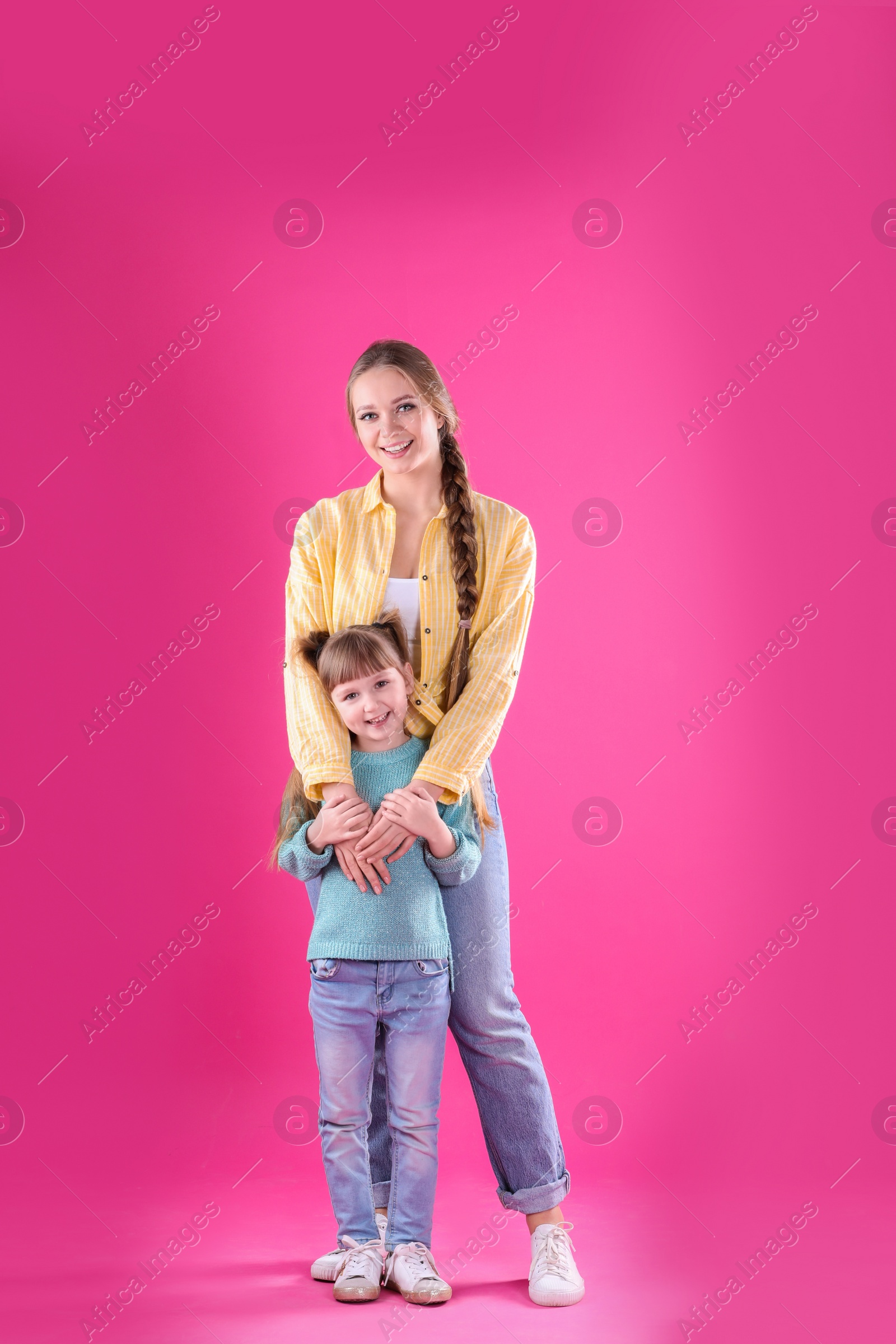 Photo of Happy woman and daughter in stylish clothes on color background