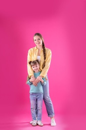 Photo of Happy woman and daughter in stylish clothes on color background