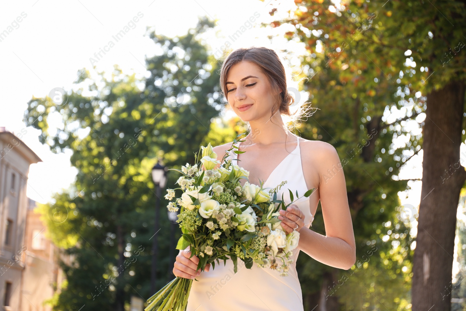 Photo of Gorgeous bride in beautiful wedding dress with bouquet outdoors