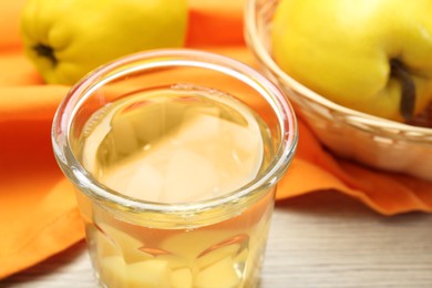 Delicious quince drink in glass and fresh fruits on wooden table, closeup