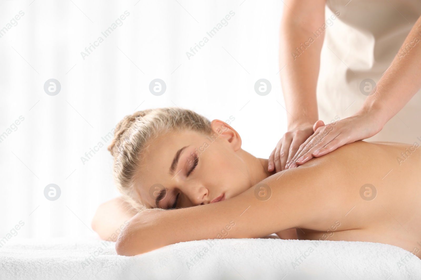 Photo of Relaxed woman receiving back massage in wellness center