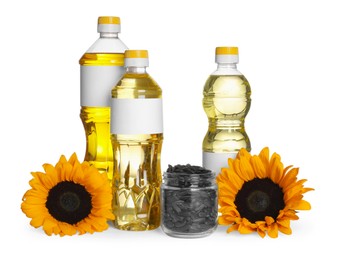 Bottles of sunflower cooking oil, seeds and yellow flowers on white background