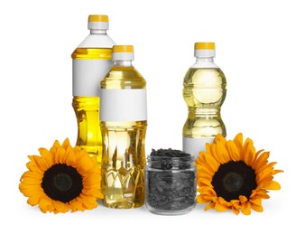 Photo of Bottles of sunflower cooking oil, seeds and yellow flowers on white background