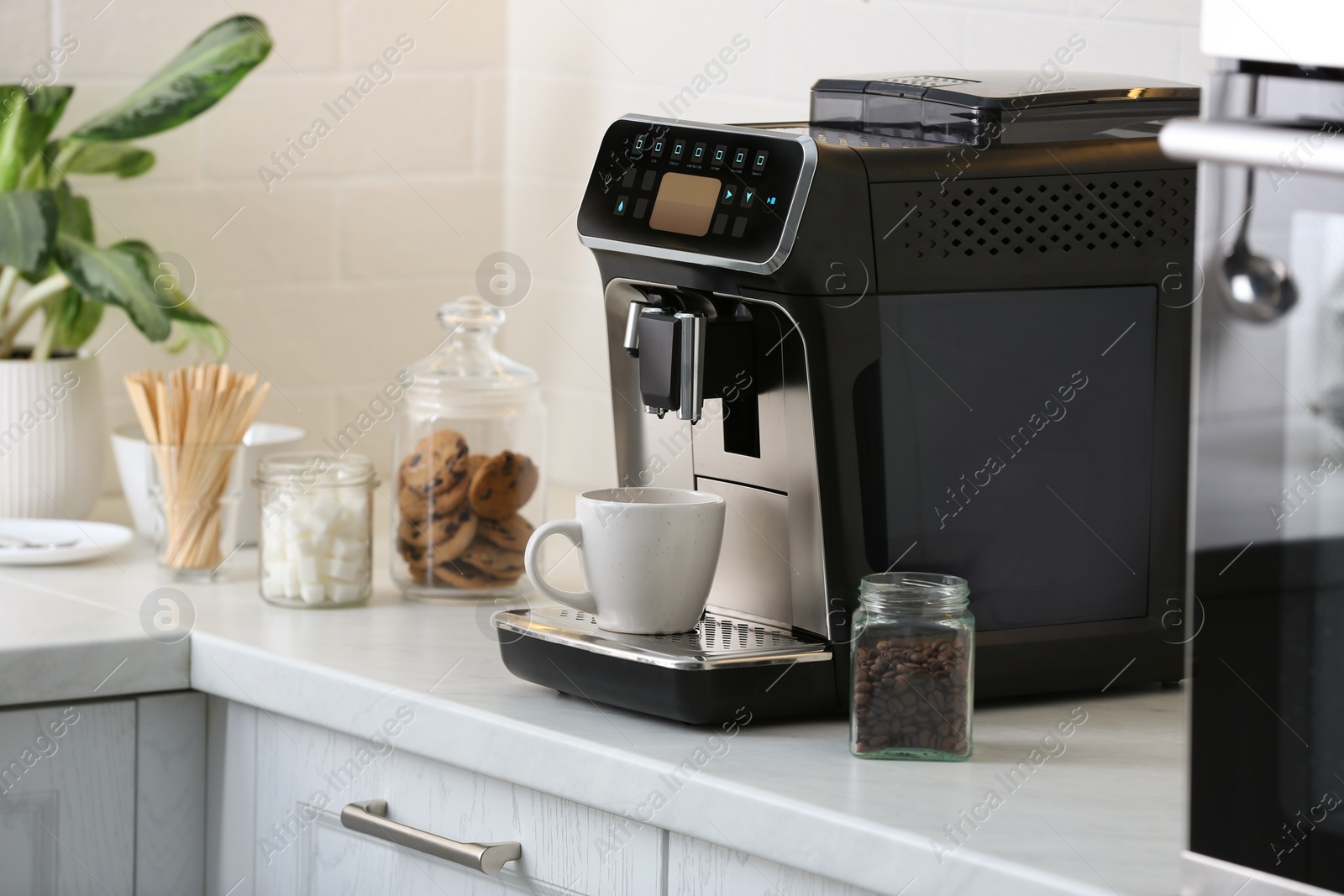 Photo of Modern electric coffee machine with cup on white countertop in kitchen