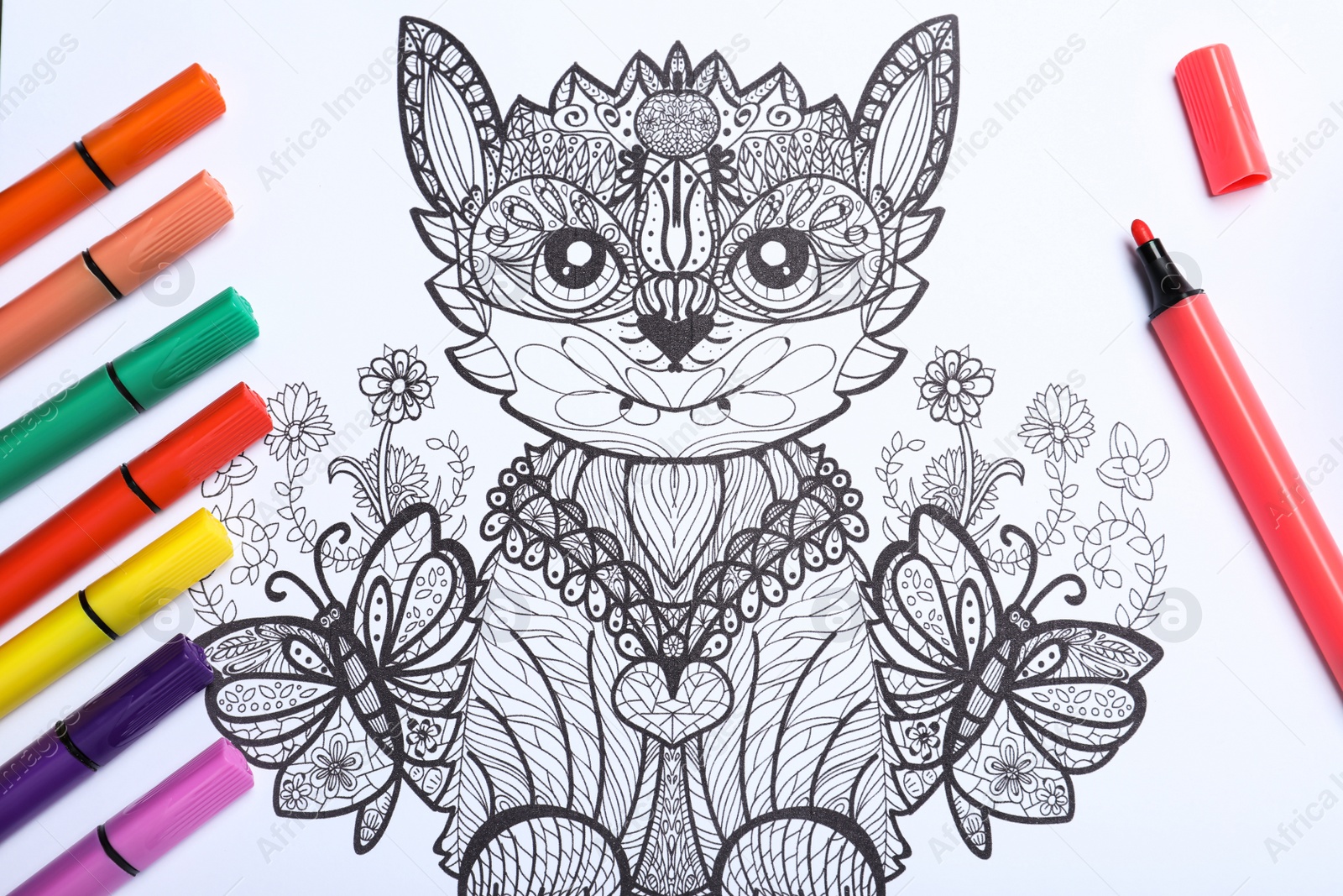 Photo of Felt tip pens on antistress coloring page, top view