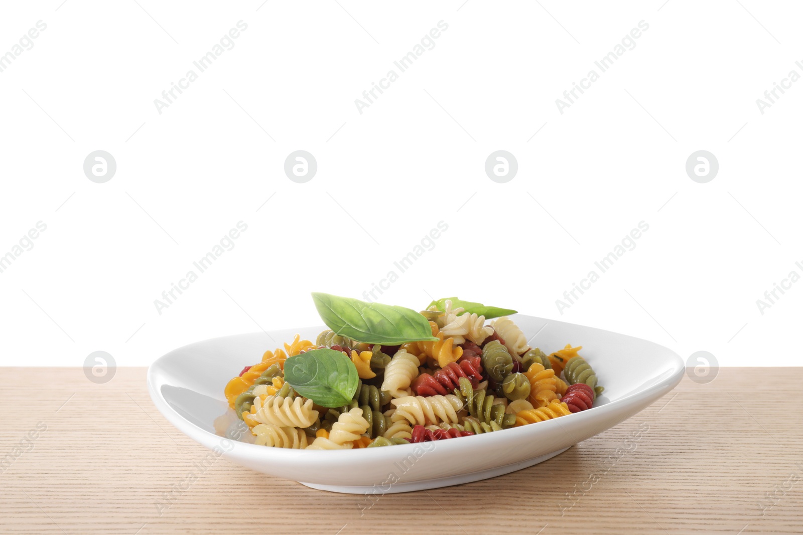 Photo of Delicious vegetable spiraline pasta with basil on wooden table