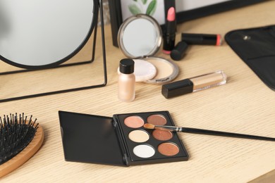 Photo of Mirror and makeup products on wooden dressing table, closeup