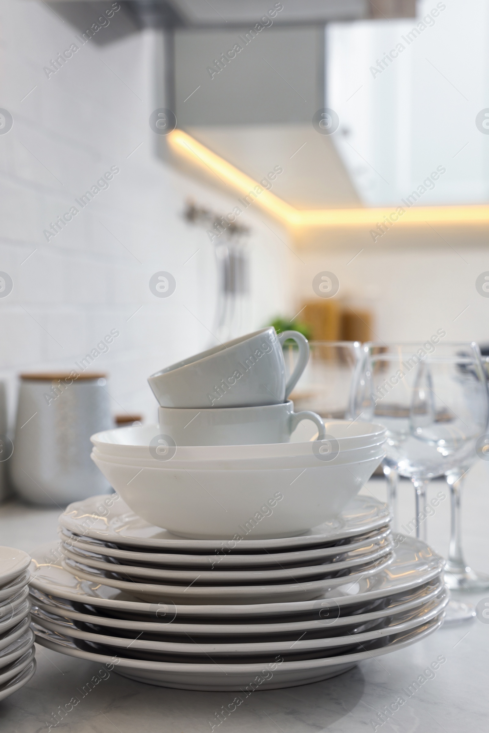 Photo of Different clean dishware, cups and glasses on countertop in kitchen
