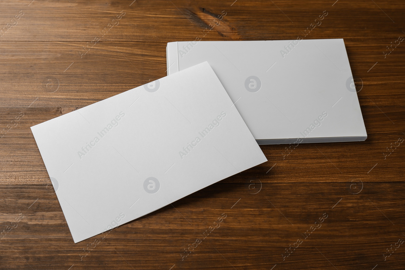 Photo of Sheet of paper and blank brochure on wooden table. Mockup for design