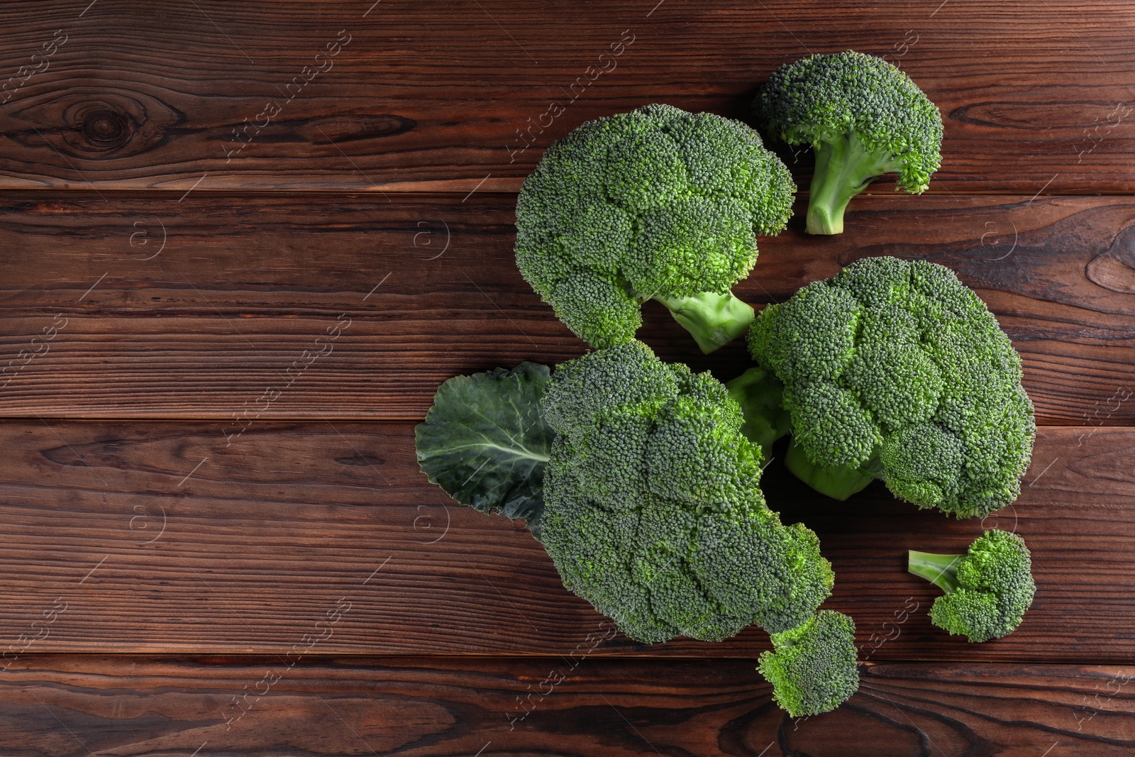 Photo of Fresh raw broccoli on wooden table, flat lay. Space for text