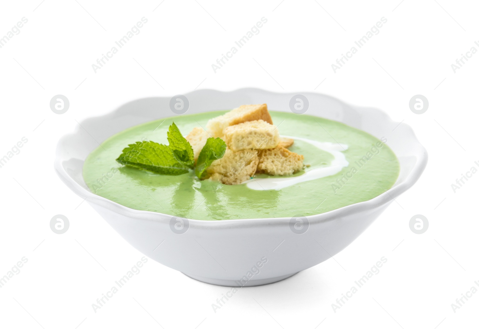 Photo of Green pea soup with croutons in bowl on white background