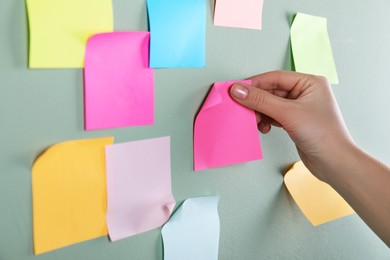Photo of Woman sticking pink note on grey wall, closeup