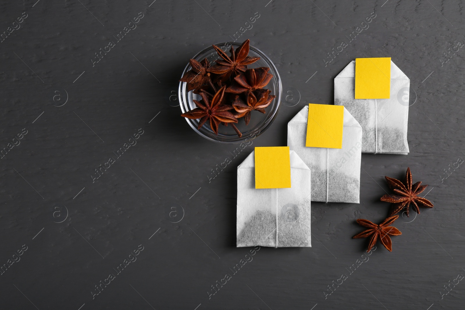 Photo of Tea bags and anise stars on grey wooden table, flat lay. Space for text