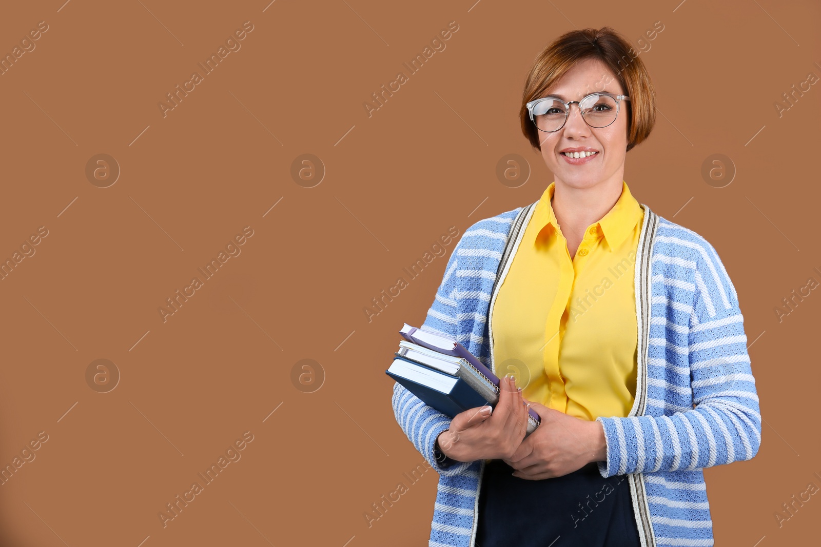 Photo of Portrait of female teacher with notebooks on color background