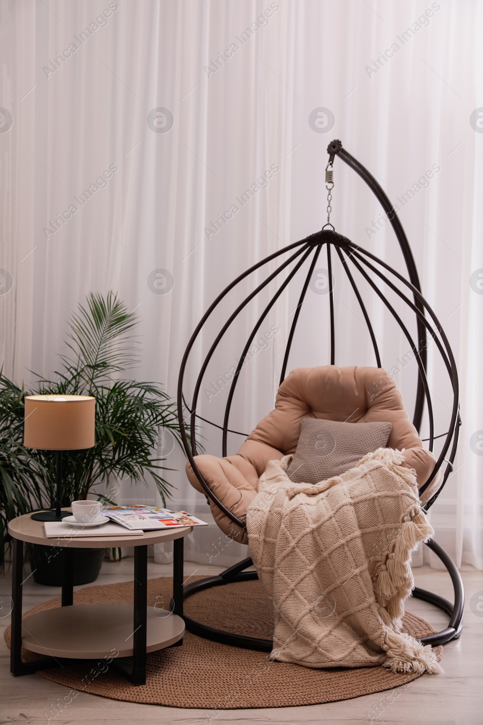 Photo of Comfortable place for rest with hanging chair near window in room