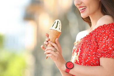 Photo of Happy young woman with delicious ice cream in waffle cone outdoors, closeup. Space for text