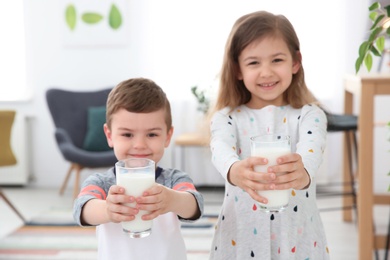 Photo of Cute little kids with glasses of milk indoors
