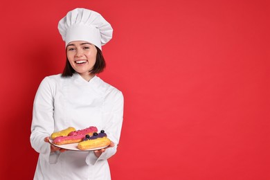 Photo of Happy confectioner with delicious eclairs on red background, space for text