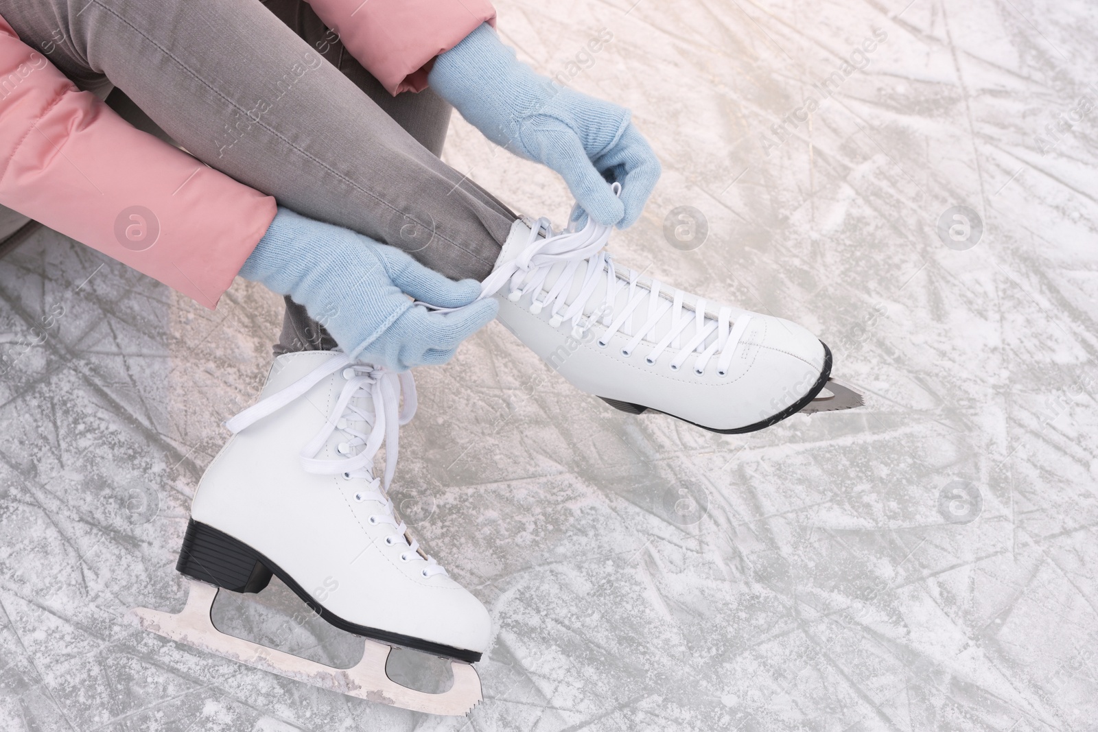 Photo of Woman lacing figure skates on ice, closeup