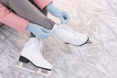 Woman lacing figure skates on ice, closeup