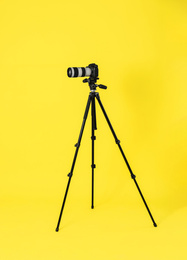 Modern professional video camera on yellow background