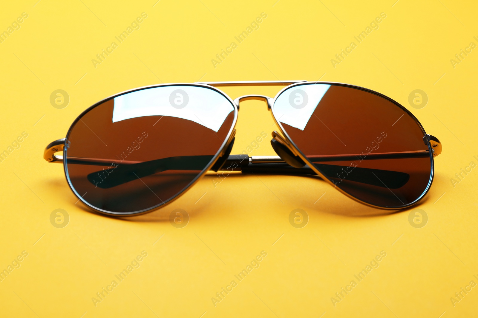 Photo of Stylish sunglasses on yellow background. Fashionable accessory