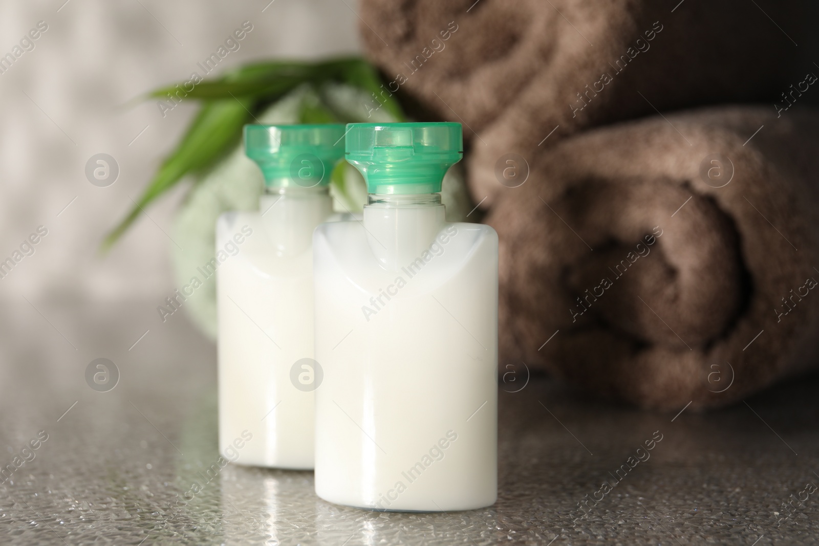 Photo of Mini bottles of cosmetic products on grey textured table