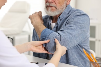 Photo of Arthritis symptoms. Doctor examining patient's elbow in hospital, closeup