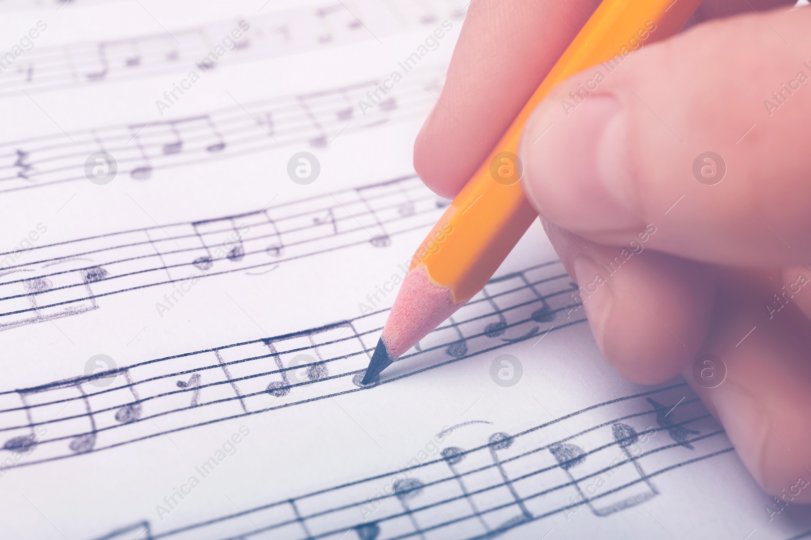 Image of Woman writing music notes on sheet with pencil, closeup