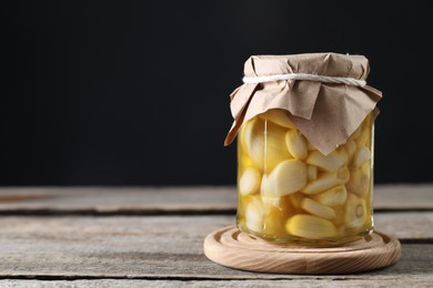 Garlic with honey in glass jar on wooden table against black background. Space for text