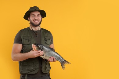 Photo of Fisherman with caught fish on yellow background, space for text