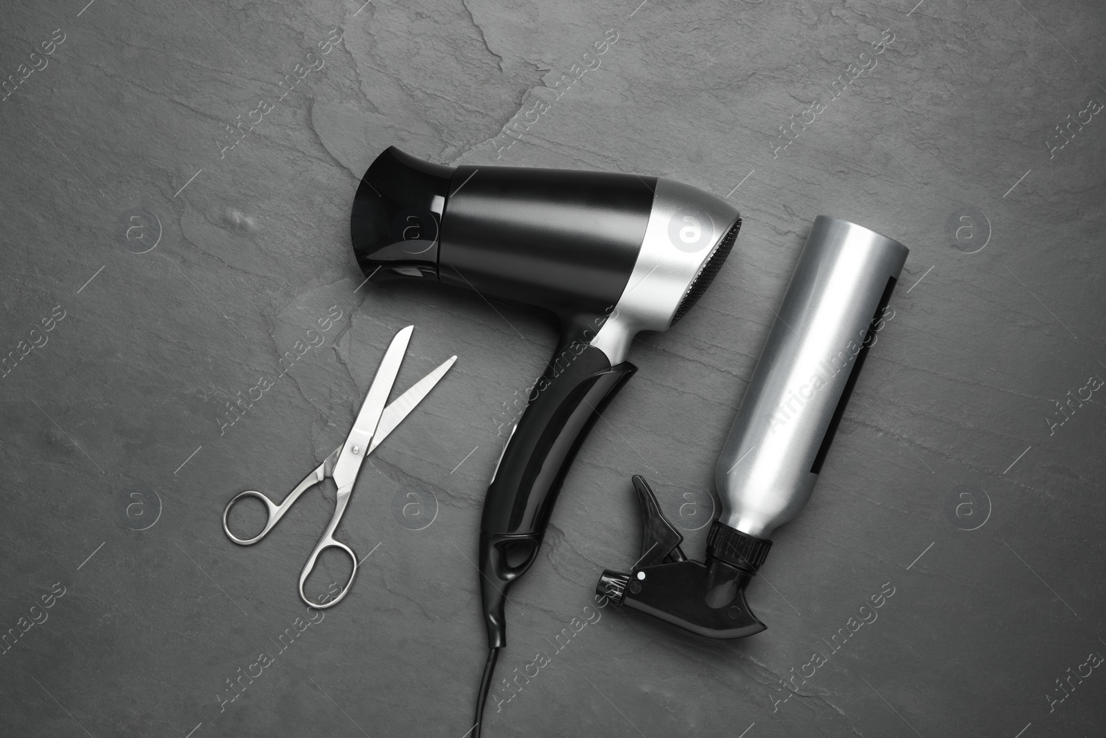 Photo of Hair dryer and professional hairdresser tools on black background, flat lay