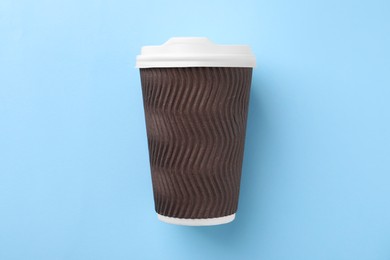 One paper cup on light blue background, top view. Coffee to go