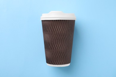 Photo of One paper cup on light blue background, top view. Coffee to go