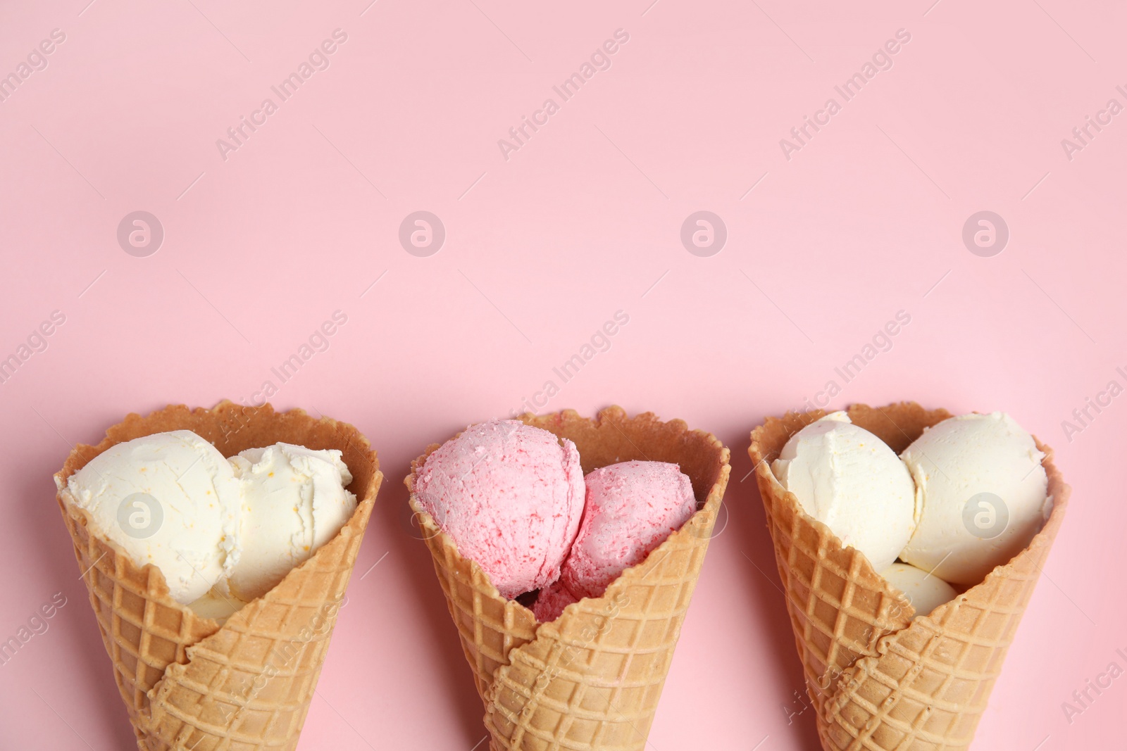 Photo of Delicious ice creams in wafer cones on pink background, flat lay. Space for text