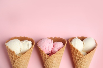 Delicious ice creams in wafer cones on pink background, flat lay. Space for text