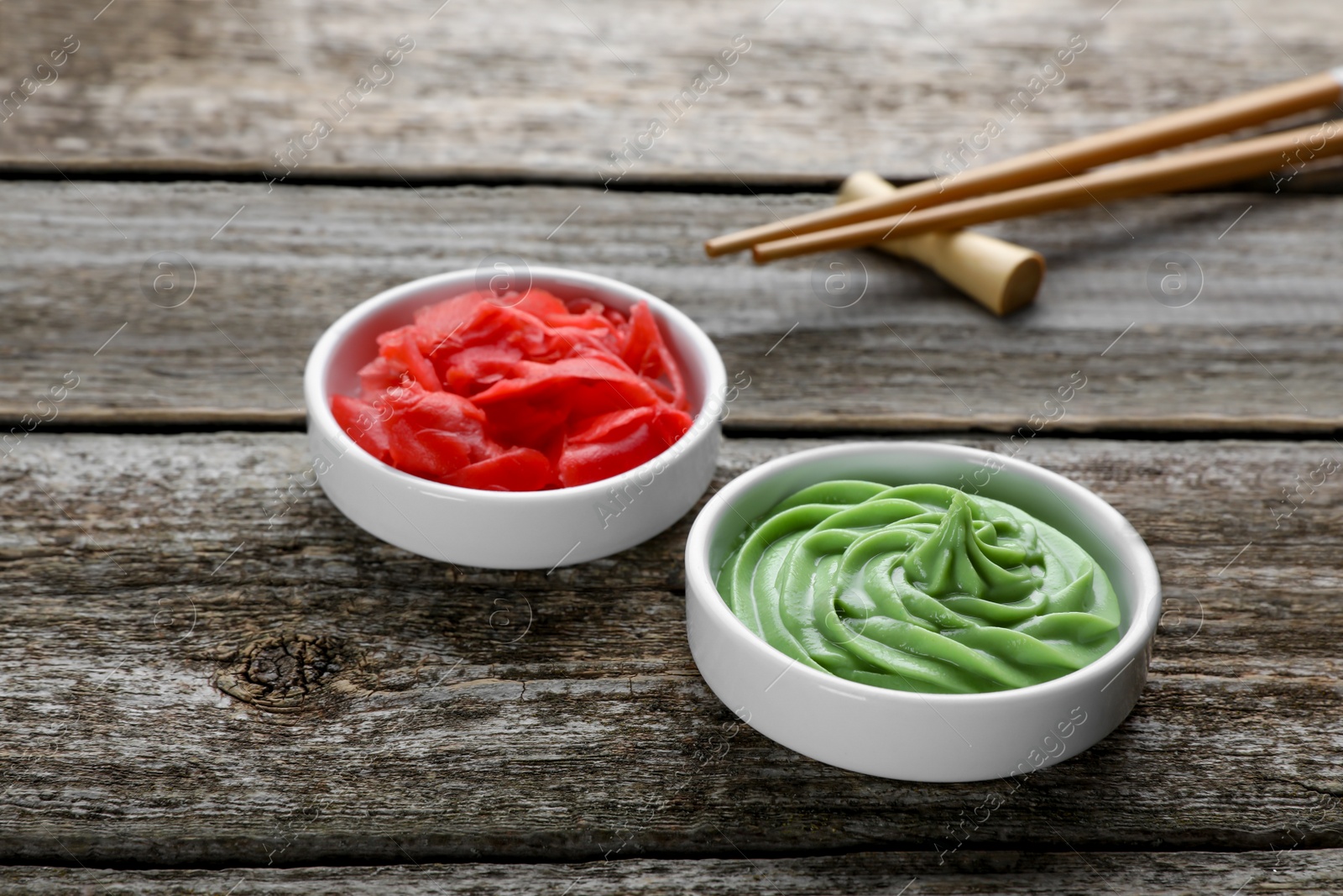 Photo of Bowls with swirl of wasabi paste and pickled ginger on wooden table